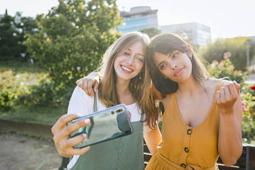 Porträt von zwei glücklichen Freunden, die ein Selfie mit einem Smartphone machen - TCEF00797