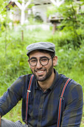 Porträt eines lächelnden jungen Mannes mit Brille und Mütze - TCF06288