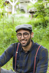 Portrait of smiling young man wearing glasses and cap - TCF06288