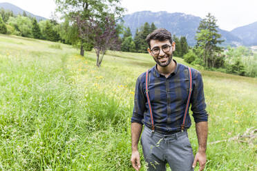 Portrait of smiling young man standing on a meadow, Reichenwies, Oberammergau, Gerrmany - TCF06291