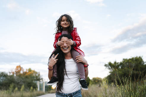 Mother with daughter on her shoulders, girl covering her eyes - EGAF00282