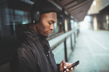 Man Listening Music On Headphones While Leaning On Window - EYF07741