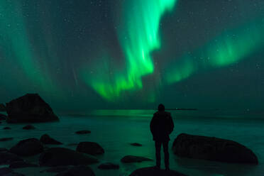 Rückansicht der Silhouette Mann stehend am Ufer gegen Aurora Borealis - EYF07748