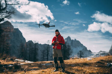 Mann fliegt mit Drohne gegen Berge - EYF07764