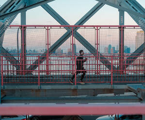 Seitenansicht des Mannes läuft auf der Brücke bei Sonnenuntergang - EYF07795