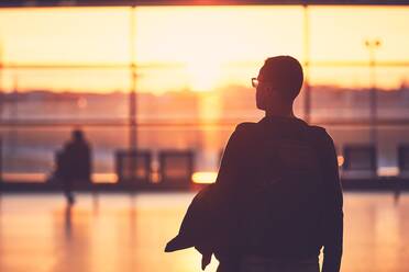 Rückansicht eines Mannes auf dem Flughafen bei Sonnenuntergang - EYF07804
