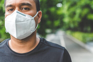 Close-Up Portrait Of Man Wearing Pollution Mask While Standing Against Trees - EYF07827