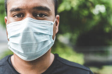 Close-Up Portrait Of Man Wearing Pollution Mask While Standing Against Trees - EYF07828