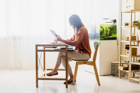 Female freelancer working at home sitting at desk using tablet - ERRF04018
