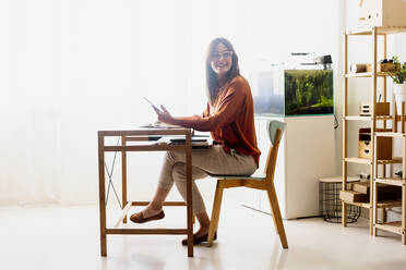 Female freelancer working at home sitting at desk using tablet - ERRF04019