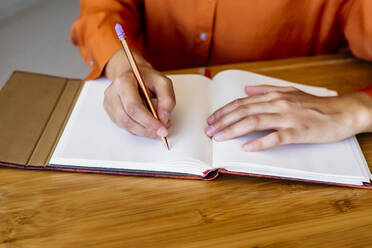 Close-up of woman sitting at desk taking notes - ERRF04051