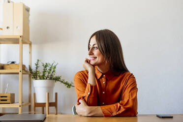 Smiling female freelancer sitting at desk at home having a break - ERRF04063