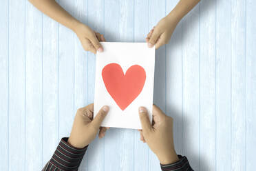 Cropped Image of Couple Holding Paper With Heart Shape On Table - EYF07844