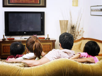 Rear View Of Family Sitting On Sofa At Home - EYF07869