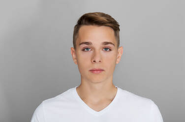 Porträt eines jungen Mannes, der vor einem grauen Hintergrund steht - EYF07898