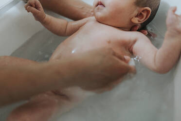 Cropped Hands Bathing Baby Girl In Bathtub At Home - EYF07904
