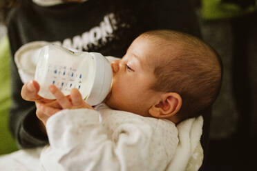 Cropped Hand Feeding Milk To Baby Girl With Bottle At Home - EYF07905