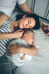 Family Sleeping On Bed At Home - EYF07918