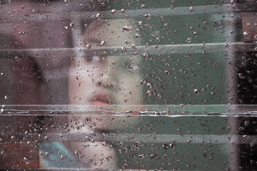 Close-Up Of Thoughtful Woman Seen Through Wet Window - EYF07921