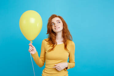 Thoughtful Young Woman Holding Balloons Against Blue Background - EYF07923