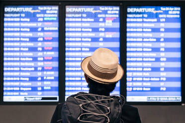 Rear View Of Man Wearing Hat Blick auf Gerät Bildschirme am Flughafen - EYF07963