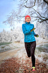Full Length Of Woman Jogging On Field During Winter - EYF07965