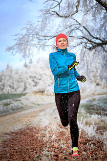 Volle Länge der Frau Joggen auf Feld im Winter - EYF07965