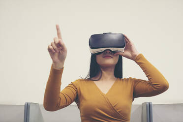 Frau trägt Virtual-Reality-Simulator, während sie gegen den klaren Himmel zeigt - EYF07972