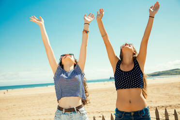 Glückliche weibliche Freunde genießen am Strand während des sonnigen Tages - EYF07976