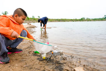 Boy Removing Plastic Bottles From Lake - EYF07985