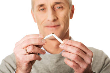 Nahaufnahme eines Mannes, der eine Zigarette vor weißem Hintergrund zerbricht - EYF08007