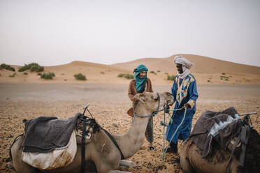 Tourist mit Führer berührt Kamel in der Wüste - EYF08012