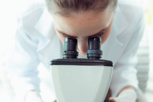 Close-Up Of Female Scientist Looking Through Laboratory Equipment - EYF08053