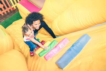 High Angle View Of Father And Daughter Playing At Bouncy Castle - EYF08058