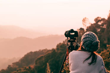 Rückansicht von Mid Adult Frau fotografieren, während stehend auf Berg gegen den Himmel während Sonnenuntergang - EYF08089