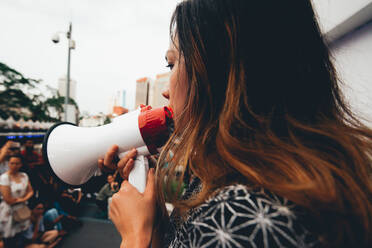 Side View Of Woman Talking On Megaphone On City Street - EYF08115