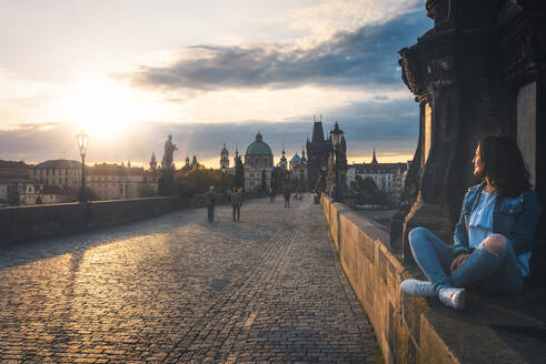 Frau sitzt auf der Karlsbrücke gegen den Himmel bei Sonnenuntergang - EYF08121