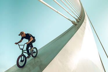 Low Angle View Of Man Riding Bicycle On Built Struktur gegen Himmel - EYF08130