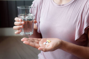 Midsection der Frau hält Glas Wasser und Pillen - EYF08144