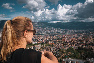 Frau mit Blick auf die Stadt Gebäude gegen bewölkten Himmel - EYF08181