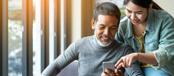 Daughter Showing Smart Phone To Father At Home - EYF08218