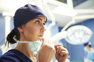 Female Doctor Wearing Surgical Mask While Standing In Operating Room - EYF08253