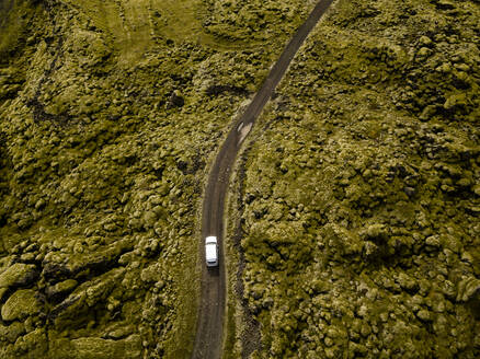 Aerial view of car driving through moss covered lava rocks in Ic - CAVF85786