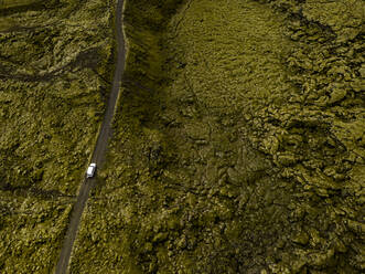 Luftaufnahme eines Autos, das durch moosbewachsene Lavafelsen in Ic fährt - CAVF85787