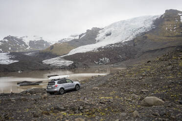 Car driving on gravel road near montain glacier - CAVF85797