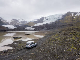 Car driving on gravel road near montain glacier - CAVF85801