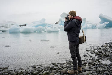 Mann beim Fotografieren der Gletscherlagune Jokulsarlon in der Abenddämmerung - CAVF85806