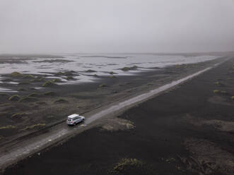 Luftaufnahme eines Autos auf einer sandigen Schotterstraße bei Stokksnes, Eis - CAVF85808