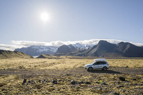 Auto auf einer Schotterstraße mit Bergen dahinter, in Island - CAVF85817