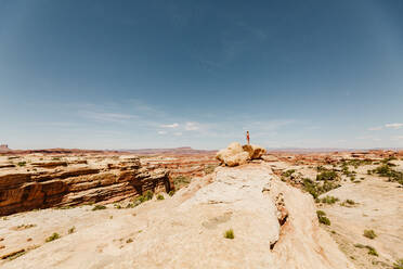 Female hiker stands atop rock overlooking red rock canyon in utah - CAVF85828